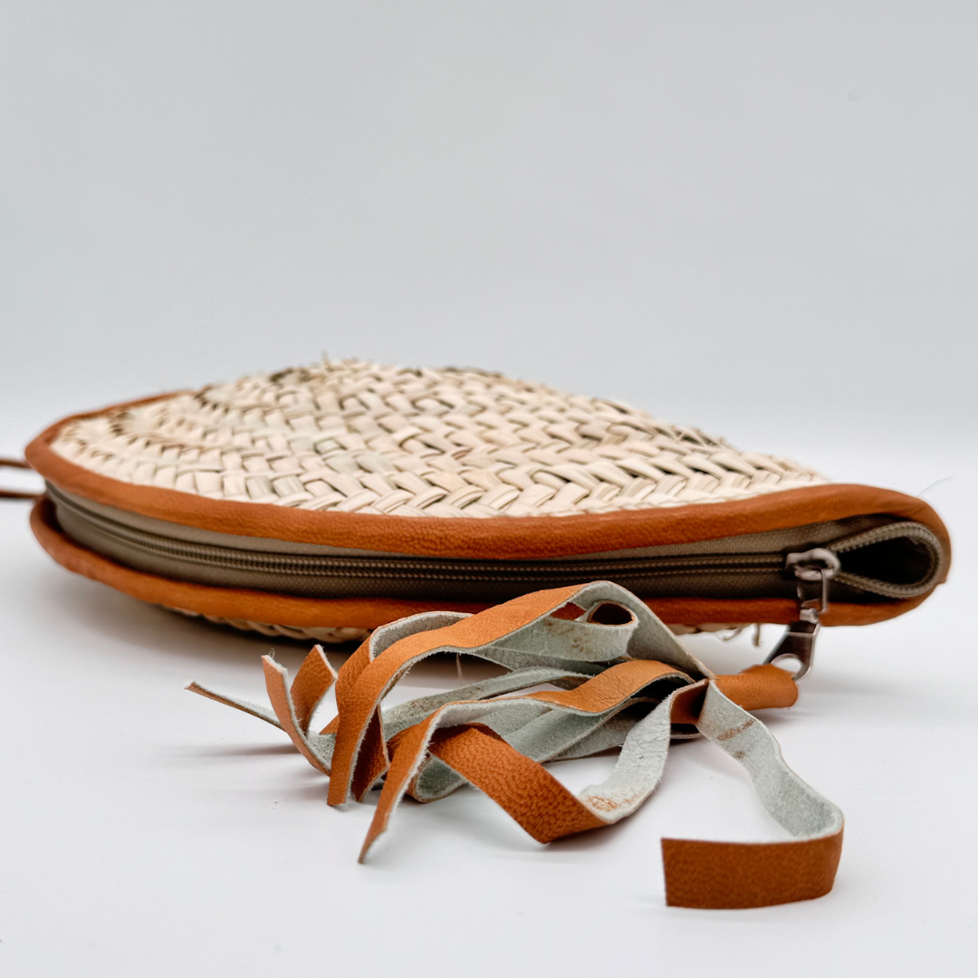 Halbmondförmige, handgewebte Strohclutch mit brauner Lederumfassung, Leder-Armbandriemen und dekorativer Quaste
