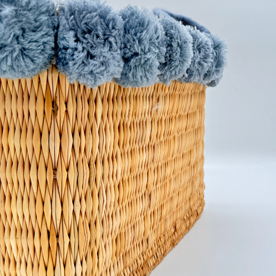 Handgewebte rechteckige Basttasche aus Naturstroh mit grauen Pompons am oberen Rand und kurzen Schlaufen aus Bast