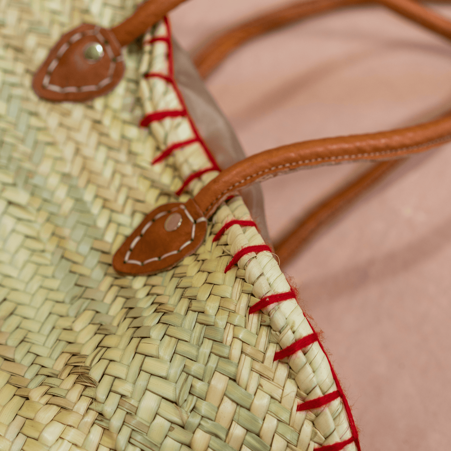 Handgewebte Basttasche aus Naturstroh mit grünen Garnstielen und roten Pompon-Kirschen sowie braunen Lederhenkeln