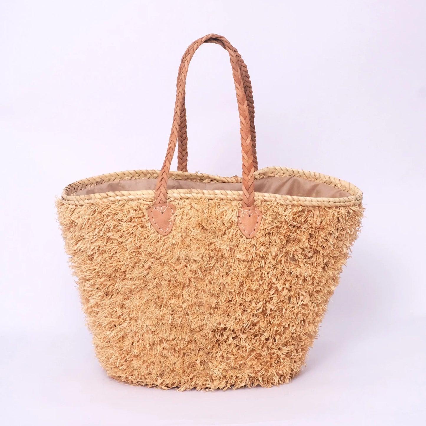 Beige, handgefertigte Basttasche aus Rafia mit shaggy Oberfläche und geflochtenen Lederhenkeln