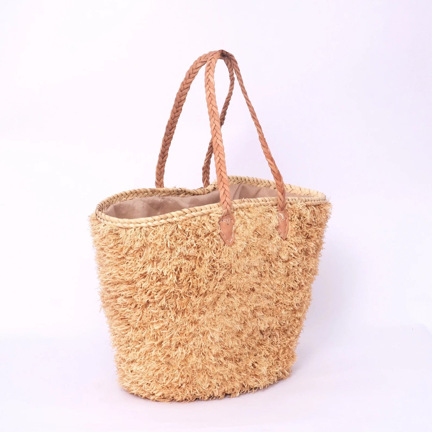Beige, handgefertigte Basttasche aus Rafia mit shaggy Oberfläche und geflochtenen Lederhenkeln