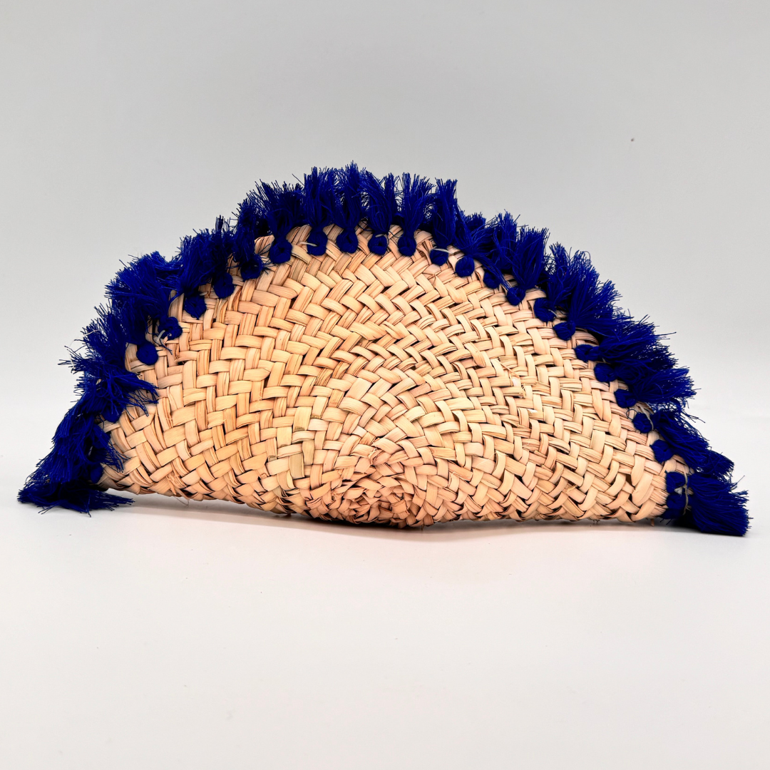 Runde, handgewebte Basttasche aus Rafia mit blauem Wildlederüberschlag, blauem Schulterriemen und dekorativer Quaste