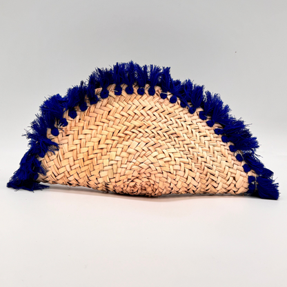 Runde, handgewebte Basttasche aus Rafia mit blauem Wildlederüberschlag, blauem Schulterriemen und dekorativer Quaste