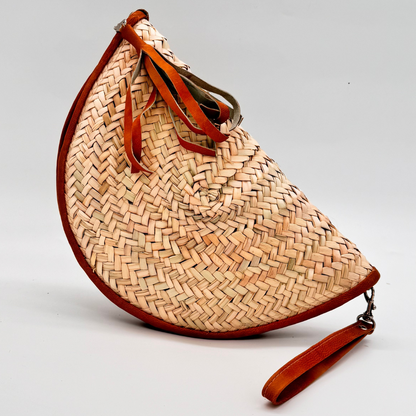 Halbmondförmige, handgewebte Strohclutch mit brauner Lederumfassung, Leder-Armbandriemen und dekorativer Quaste