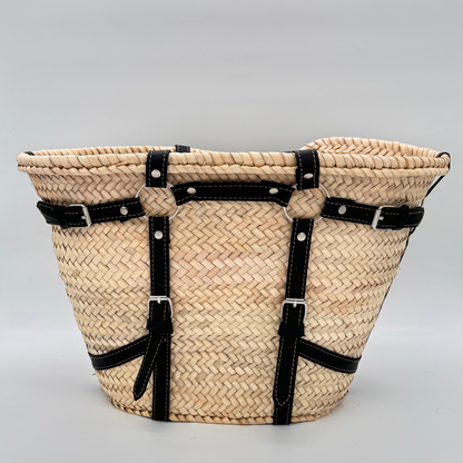 Handgewebte Strohtasche aus naturfarbenem Palmstroh mit schwarzen Lederriemen und silbernen Schnallen als dekorative Gürteldetails