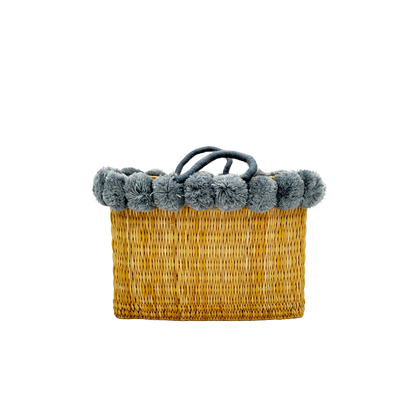 Handgewebte rechteckige Basttasche aus Naturstroh mit grauen Pompons am oberen Rand und kurzen Schlaufen aus Bast