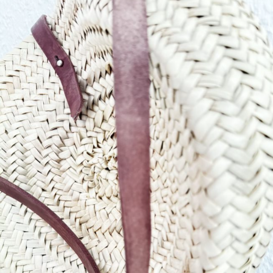 Runde, handgewebte Basttasche aus Palmstroh mit verstellbarem, schmalem braunem Lederriemen als Schultergurt