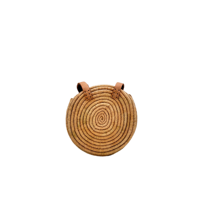 Kleine, runde Basttasche aus handgewebtem Raffia mit zwei braunen Lederlaschen zur Befestigung eines Trageriemens