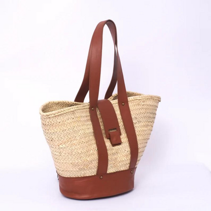 Handgewebte Strohtasche aus Palmstroh mit braunem Lederboden, zwei langen Lederhenkeln und zentralem Lederüberschlag mit Magnetverschluss