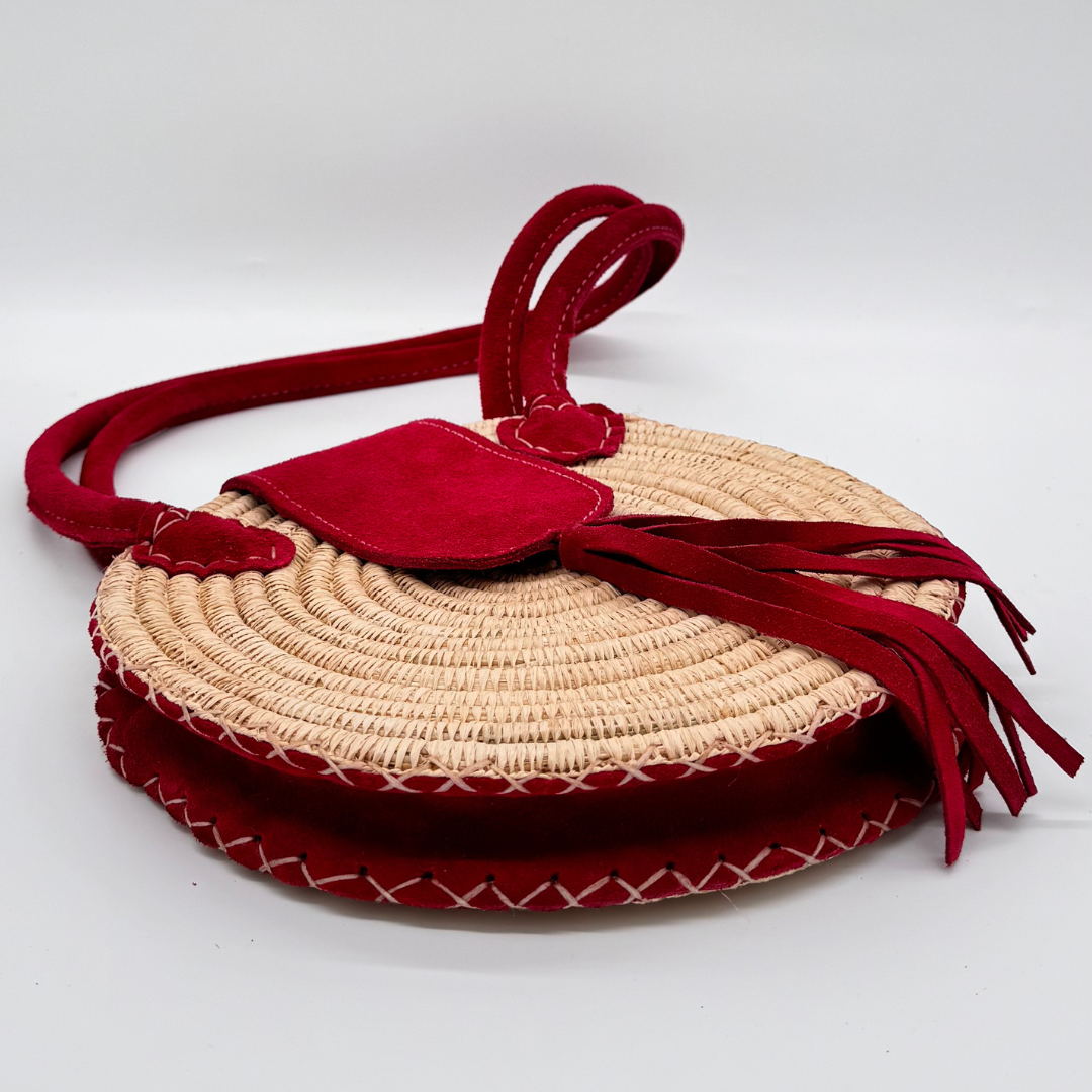 Runde, handgewebte Basttasche aus Rafia mit rotem Wildlederüberschlag, rotem Schulterriemen und dekorativer Quaste