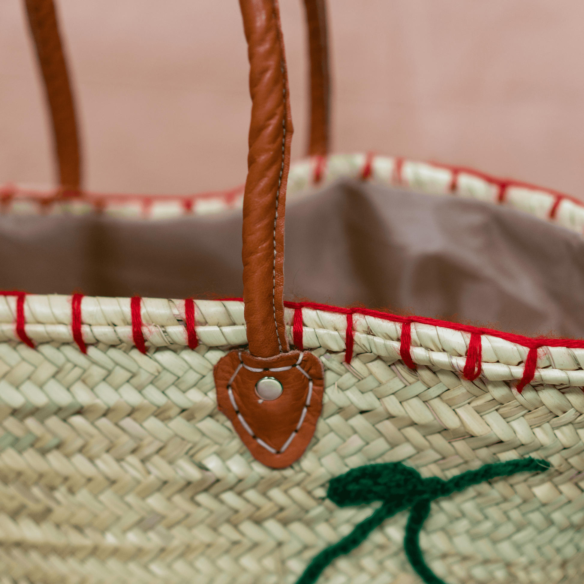 Handgewebte Basttasche aus Naturstroh mit grünen Garnstielen und roten Pompon-Kirschen sowie braunen Lederhenkeln