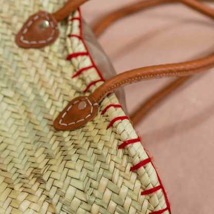 Handgewebte Basttasche aus Naturstroh mit grünen Garnstielen und roten Pompon-Kirschen sowie braunen Lederhenkeln