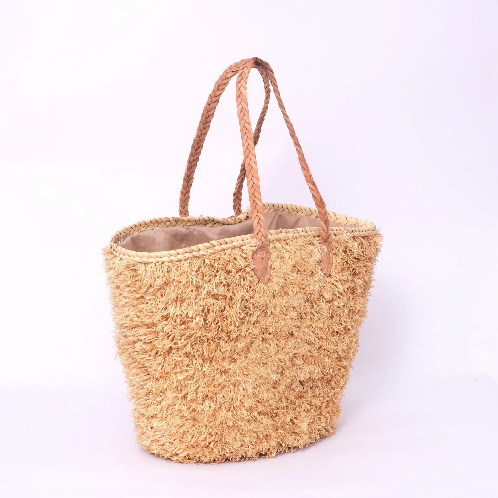 Beige, handgefertigte Basttasche aus Rafia mit shaggy Oberfläche und geflochtenen Lederhenkeln