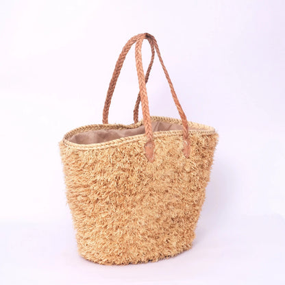 Beige, handgefertigte Basttasche aus Rafia mit shaggy Oberfläche und geflochtenen Lederhenkeln